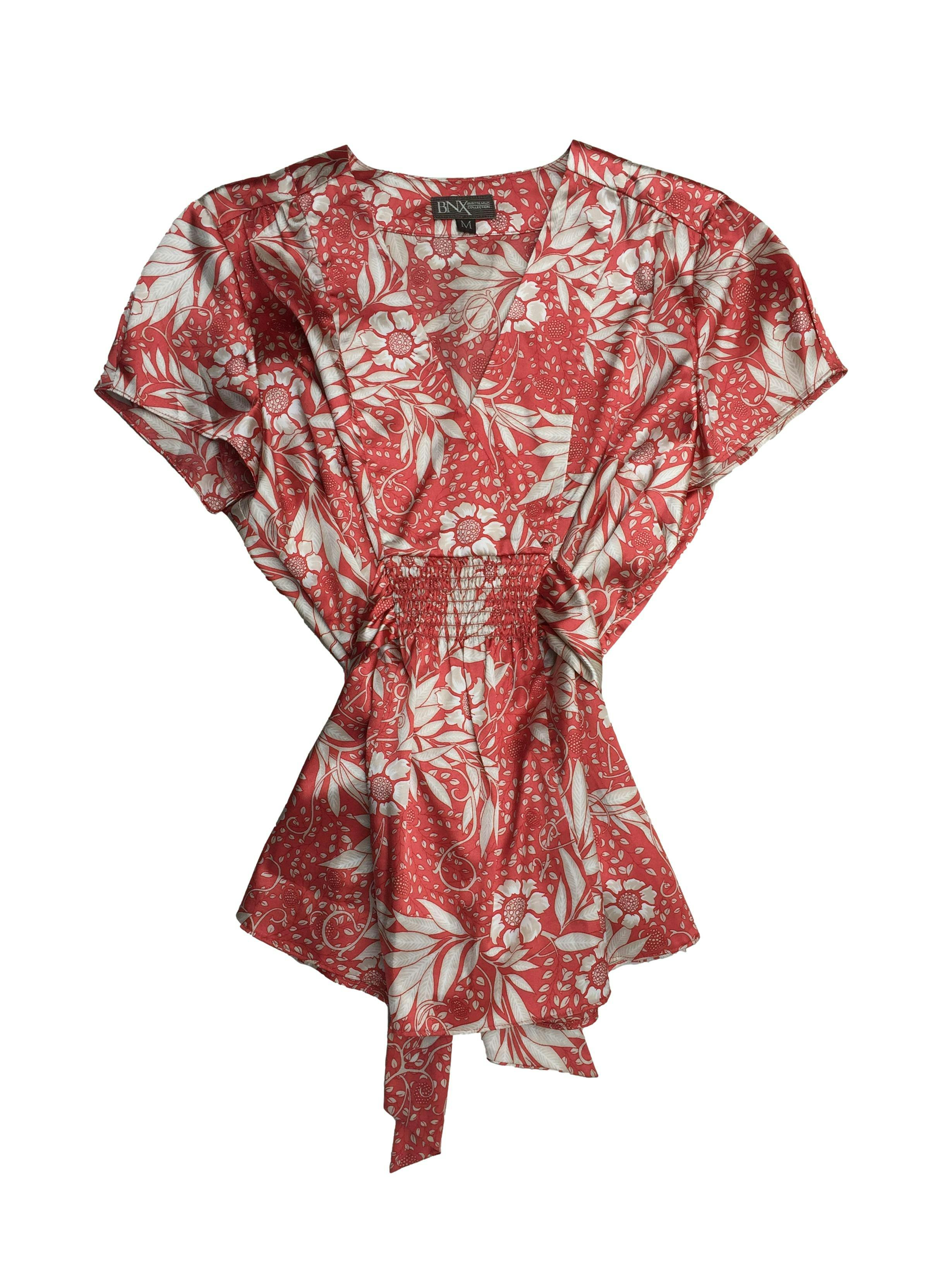 Blusa Brigitte Naux de satén coral con flores blancas, escote en V con cintos y panal de abeja en cintura, cierre lateral invisible. Busto 100cm, Largo 62cm.