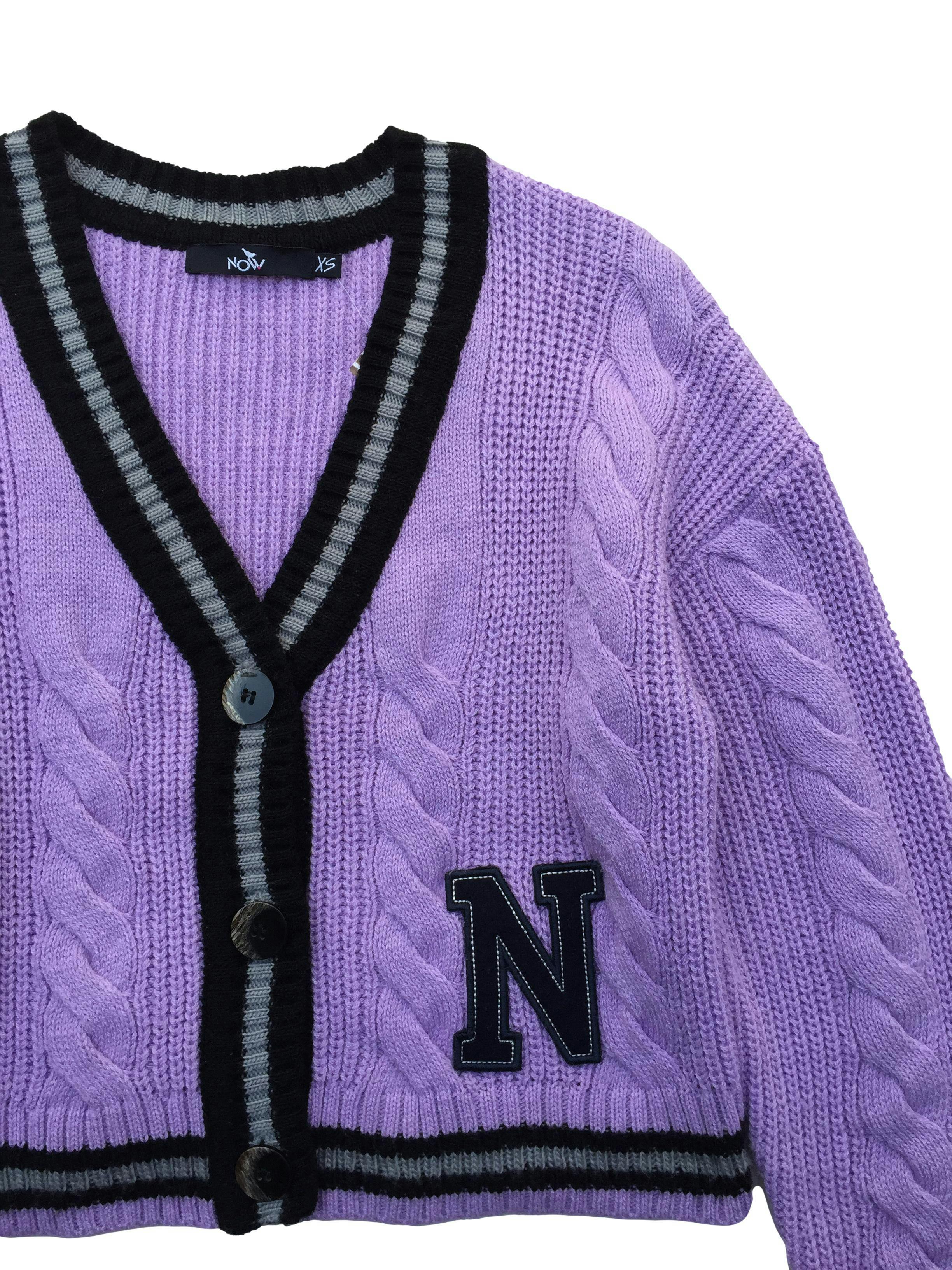 Cardigan Now oversized tejido lila con bordes negros, botones delanteros y aplicación N. Busto: 110cm, Largo: 45cm