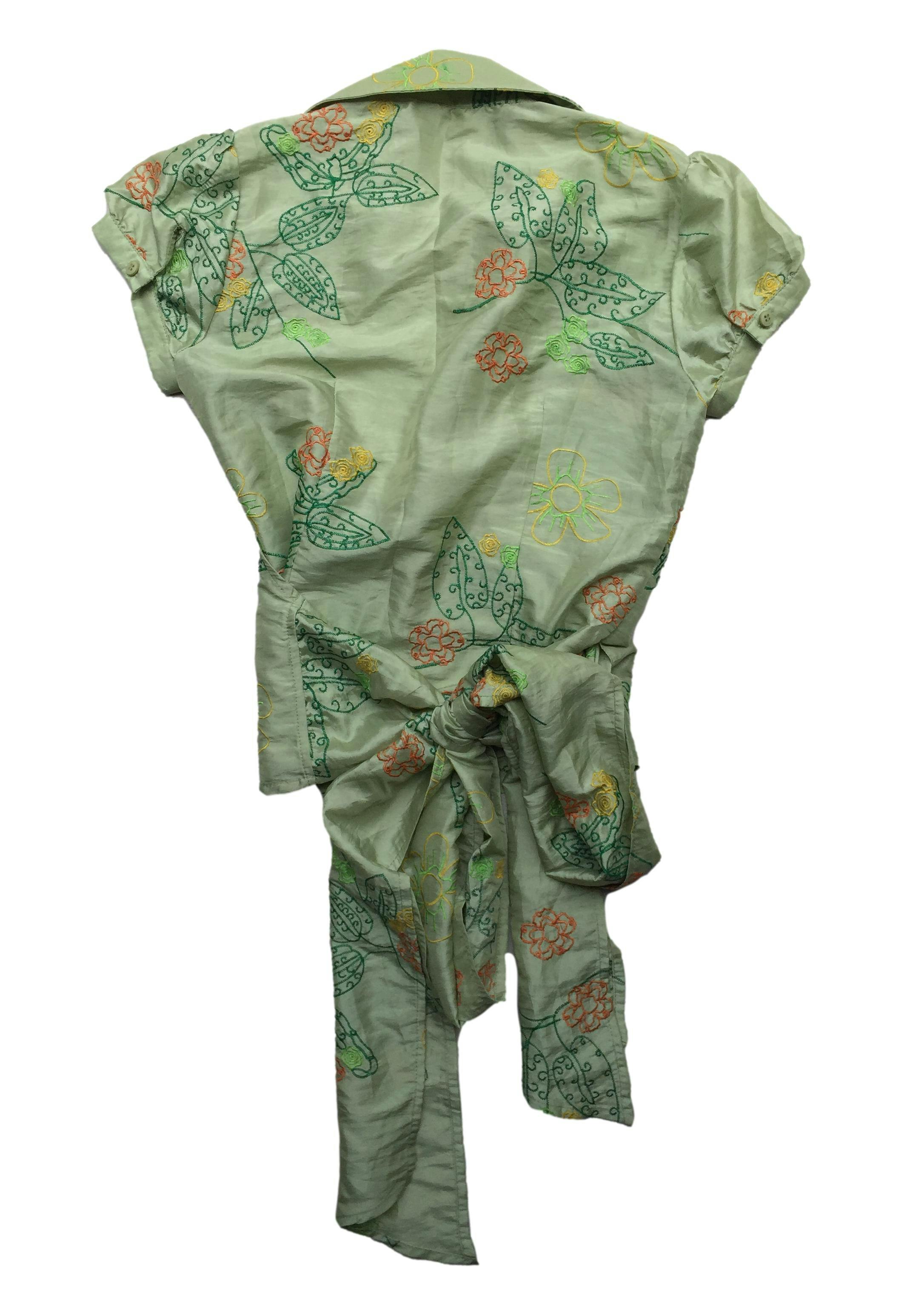 Blusa Essentiel envolvente, tela delgada color verde con bordados florales y mangas abullonadas. Busto 96cm, Largo 52cm.