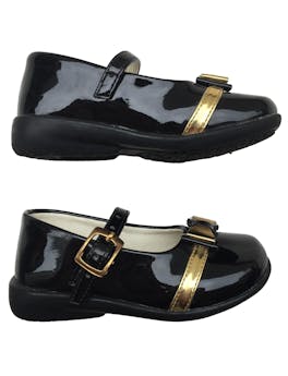 Zapatos de charol negro con correa en empeine y lazo dorado.