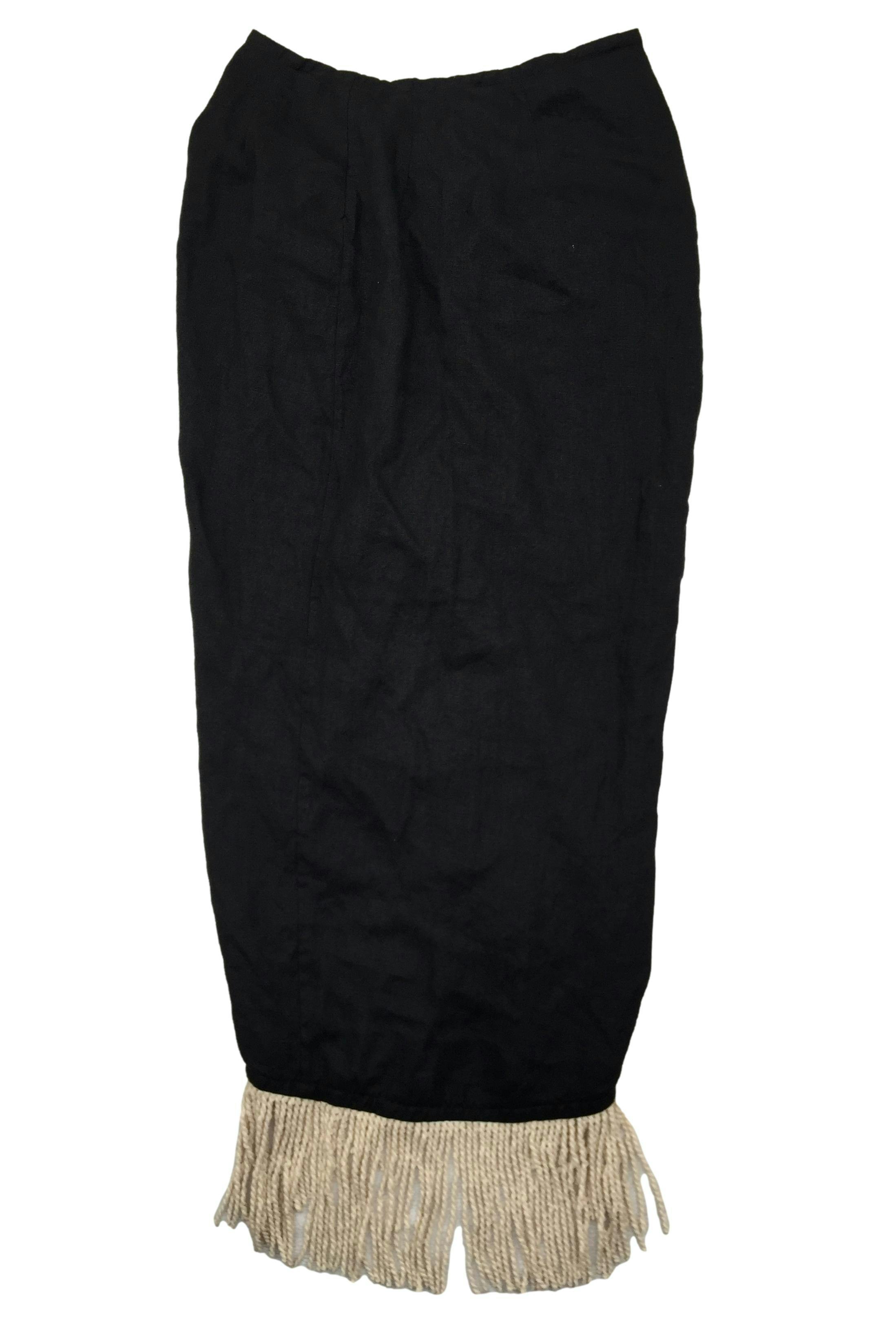 Falda negra de lino, fruncido posterior con flecos trenzados en basta asimétrica. Cintura 68 cm, Largo 85 cm.