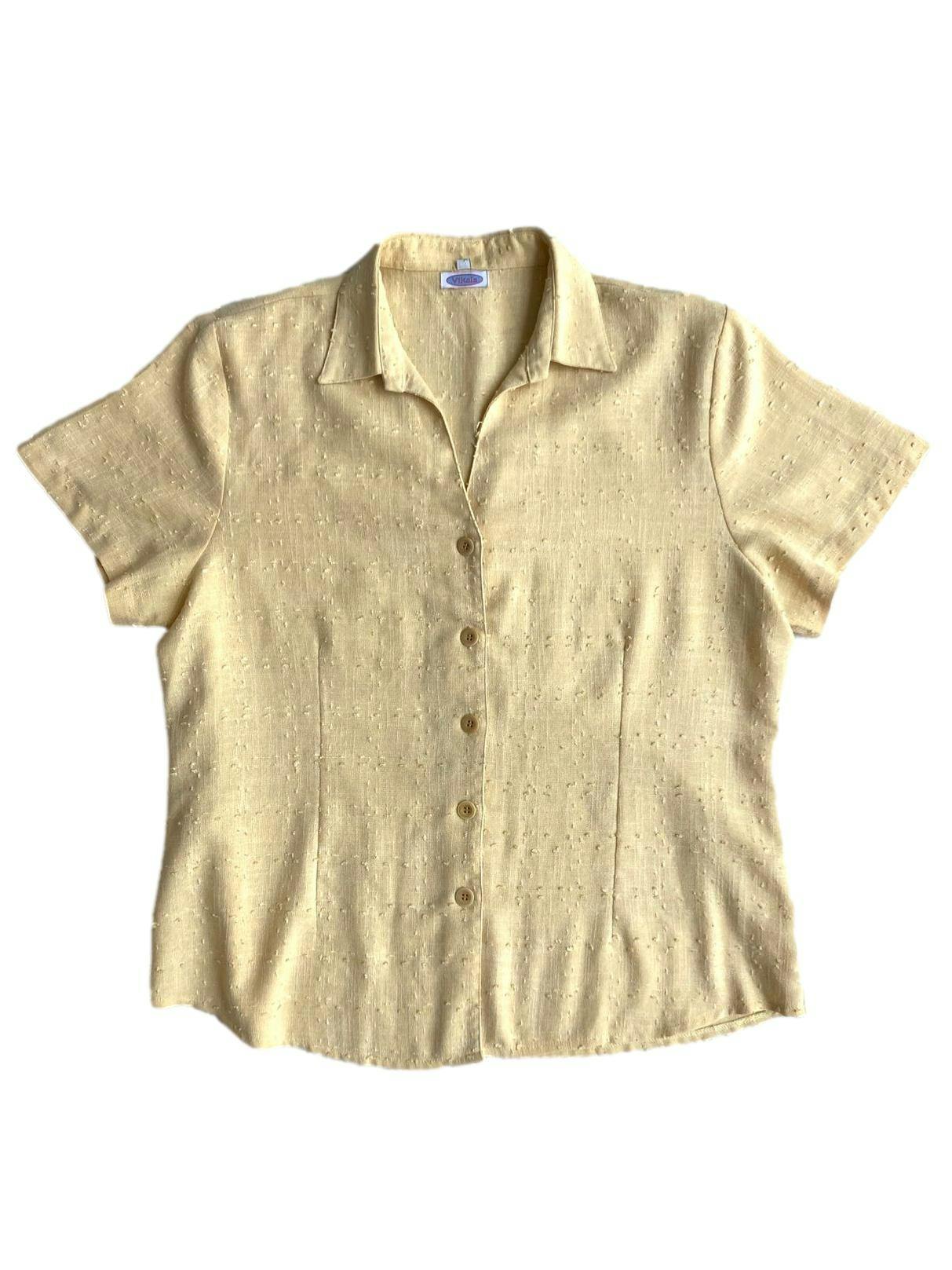 Blusa Vikals amarillo pastel con hombreras, botones delanteros, estampado de pequeñas bolitas en relieve. Busto: 104 cm, Largo: 62 cm.